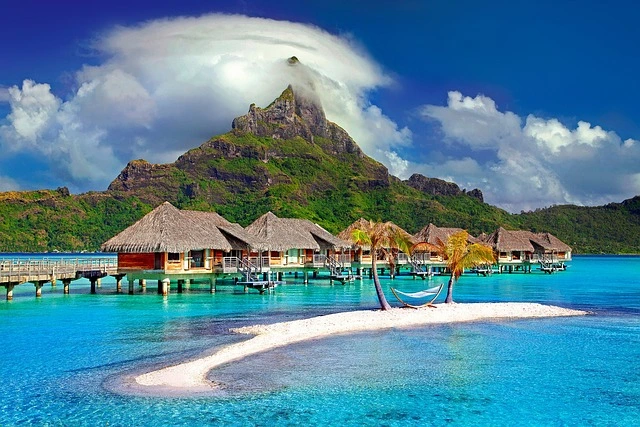 Aerial view of Bora Bora, one of the most beautiful islands, showcasing its turquoise lagoon and overwater bungalows with Mount Otemanu in the background.