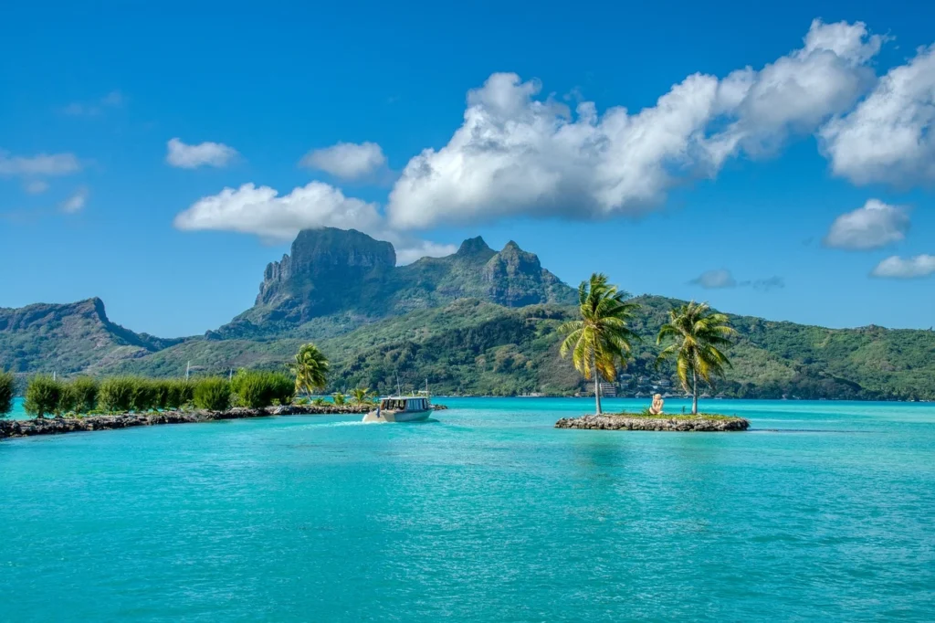 Aerial view of Bora Bora, one of the most beautiful islands, showcasing its turquoise lagoon and overwater bungalows with Mount Otemanu in the background.